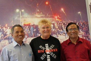 Dr Kem Thang, Helga Arntzen og U Bung Kone foran bildet av ville gledesscener i Berlin da muren falt.